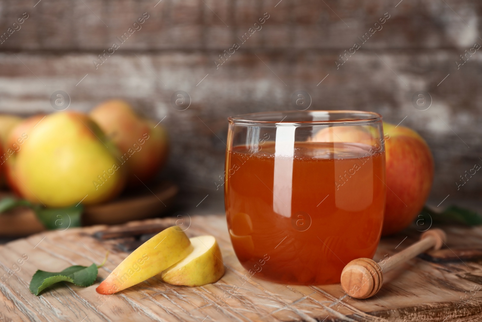 Photo of Glass of honey, apples and dipper on wooden table