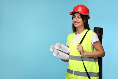 Architect in hard hat with drafts and tube on light blue background, space for text