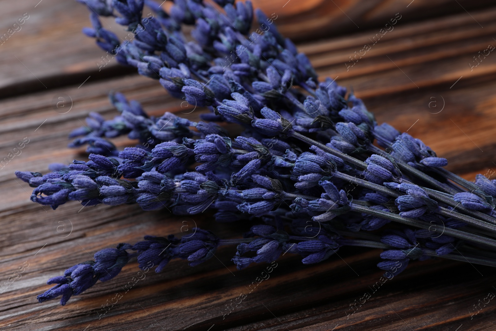 Photo of Bouquet of beautiful preserved lavender flowers on wooden table, closeup