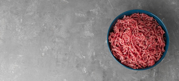 Photo of Bowl of raw minced meat on grey table, top view. Space for text
