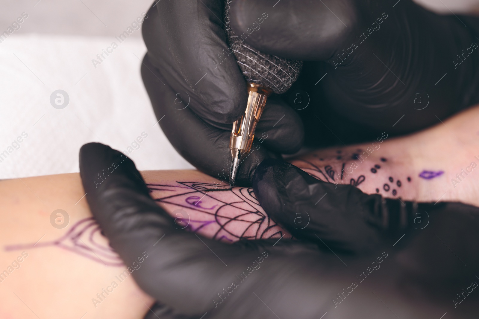 Photo of Professional artist making tattoo on hand, closeup