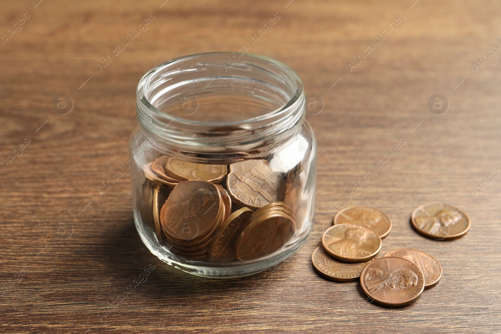 Photo of Glass jar with coins on wooden table