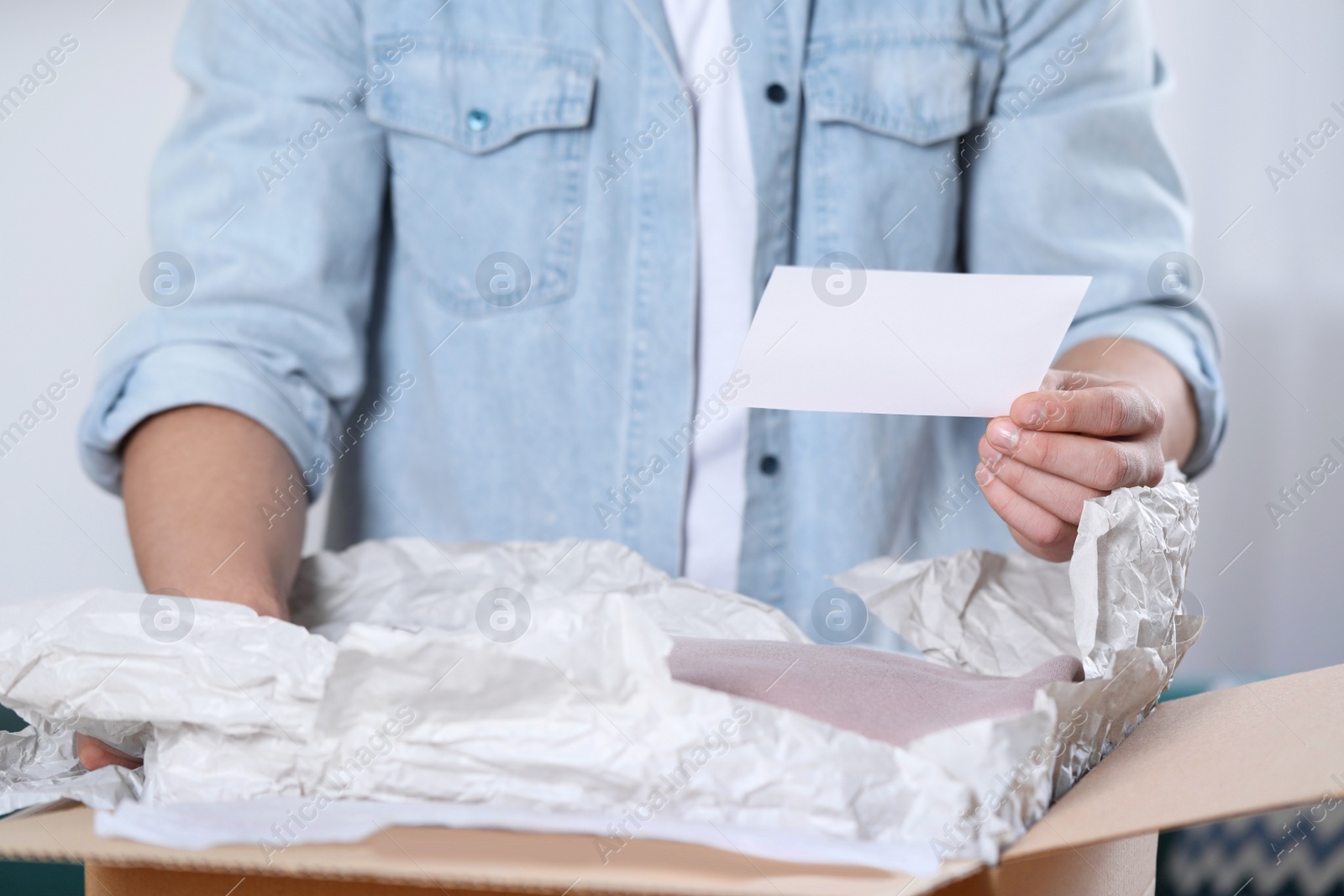 Photo of Man holding greeting card near parcel with Christmas gift, closeup