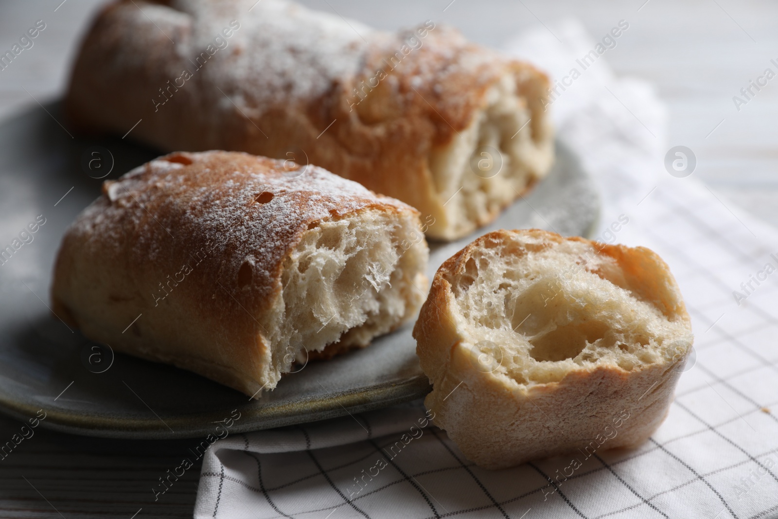 Photo of Fresh crispy ciabattas on white wooden table, closeup