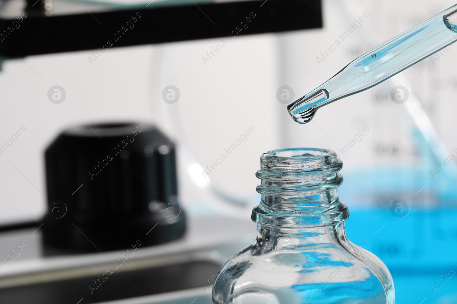 Photo of Dripping liquid from pipette into bottle in laboratory, closeup. Space for text