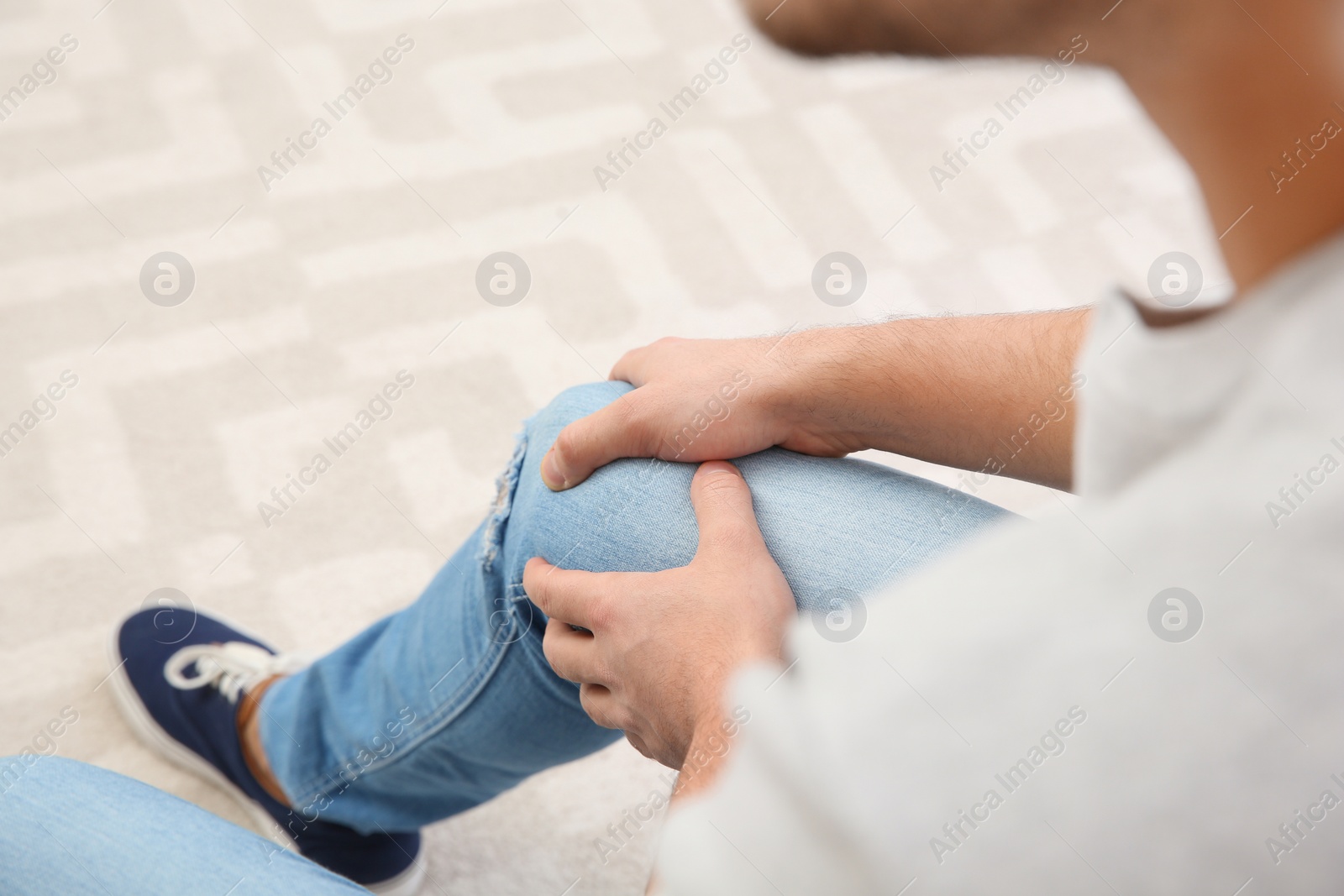 Photo of Man suffering from leg pain at home, closeup