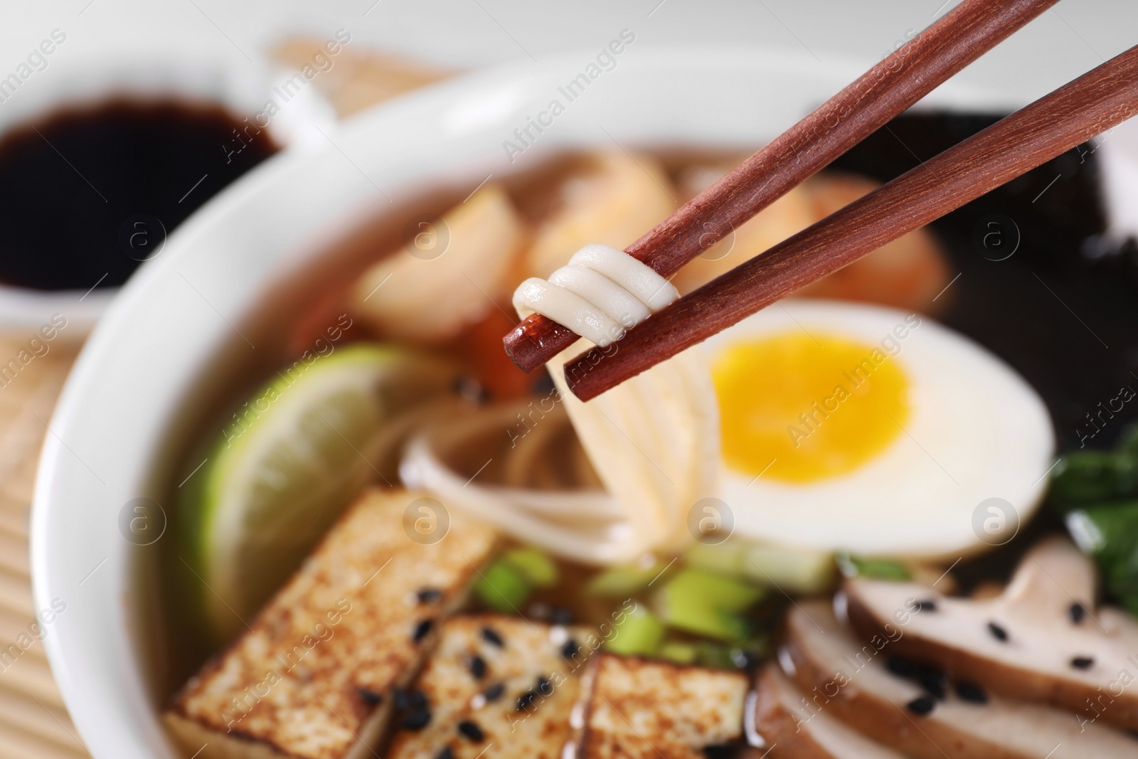 Photo of Eating delicious ramen with chopsticks, closeup. Noodle soup