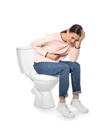 Photo of Young woman suffering from digestive disorder on toilet bowl, white background