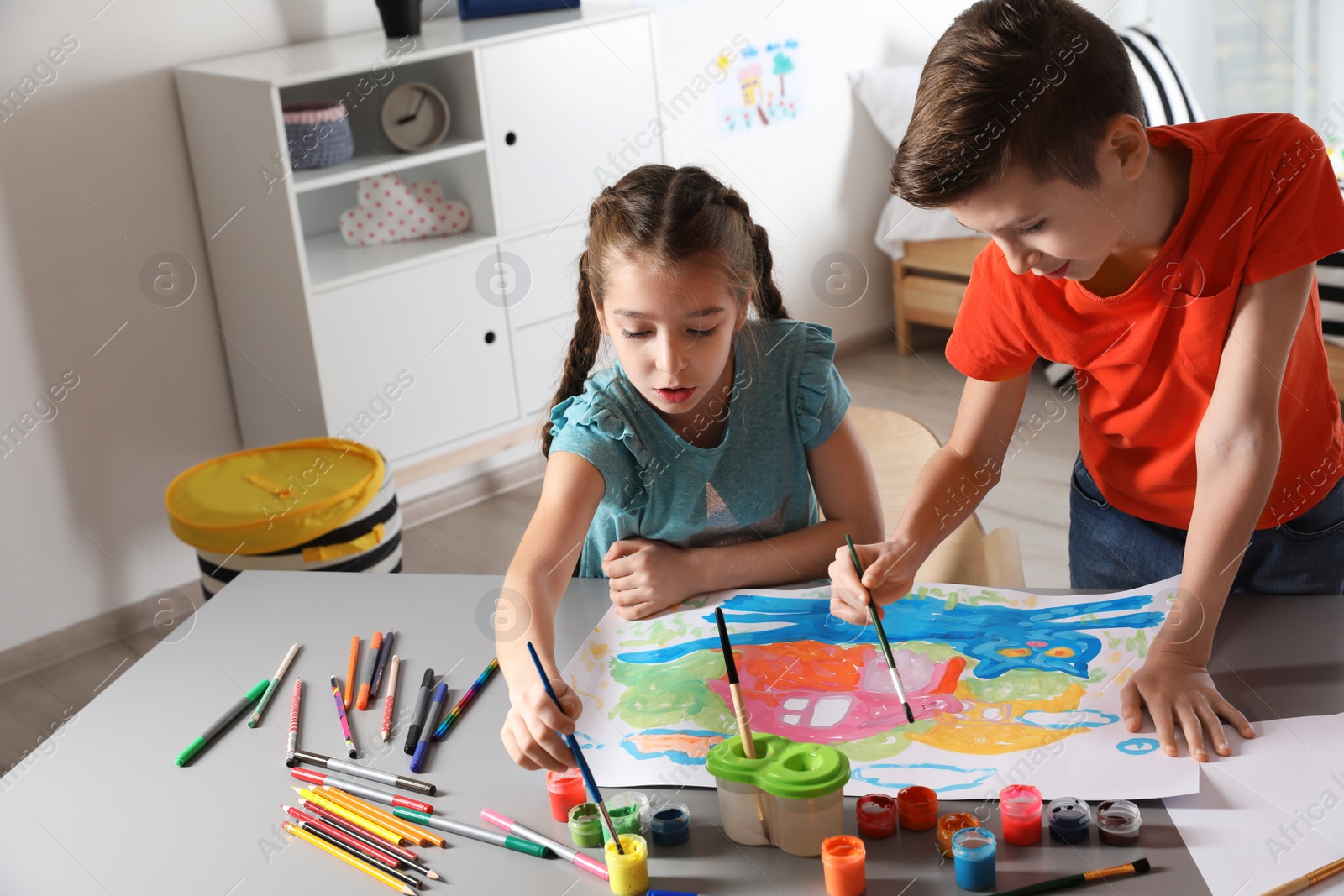 Photo of Little children painting picture at table indoors