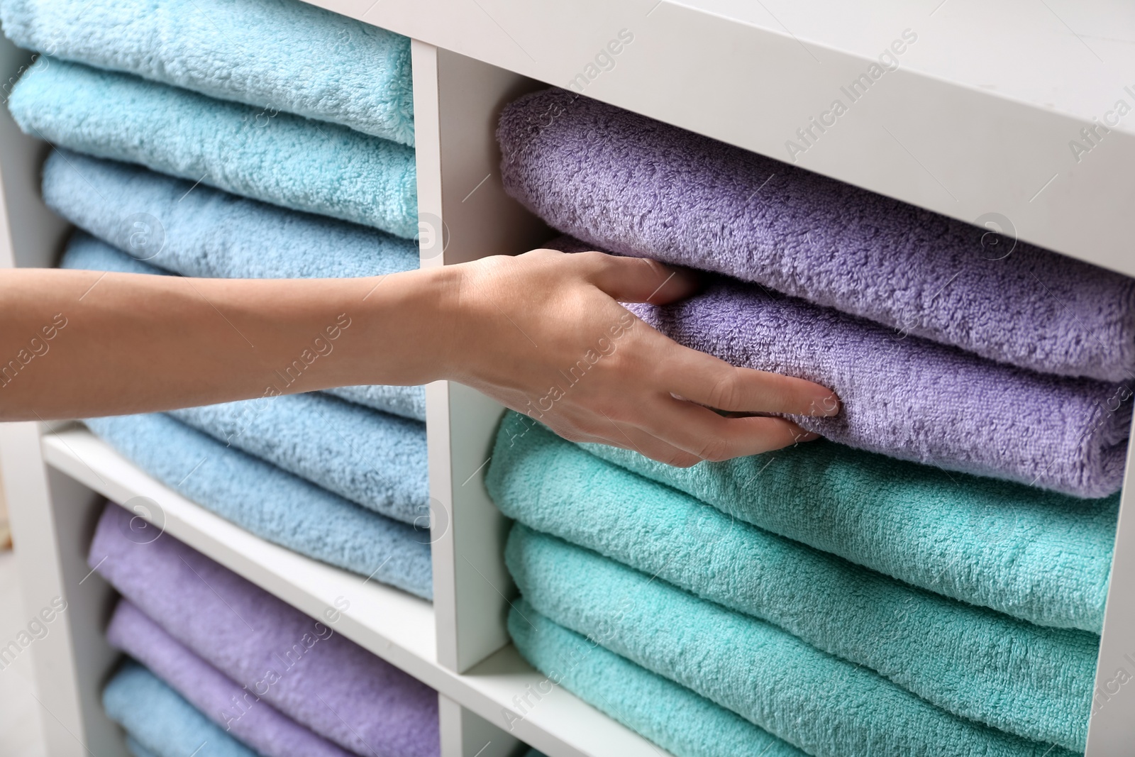 Photo of Woman taking towel from shelf, closeup view