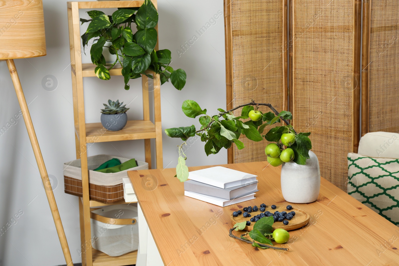 Photo of Books, blueberries and branch with green apples on wooden table in room