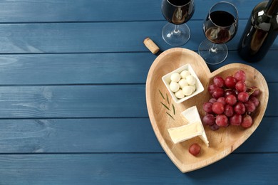 Flat lay composition with red wine and snacks on blue wooden table, space for text