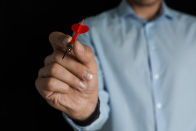 Photo of Man holding red dart on black background, closeup