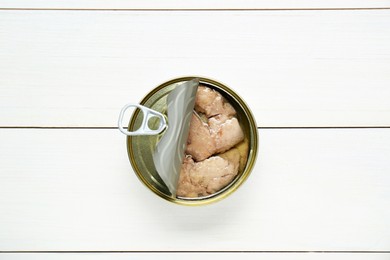 Photo of Open tin can of tasty cod liver on white wooden table, top view