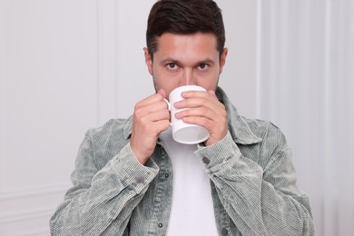 Man drinking from white mug at home