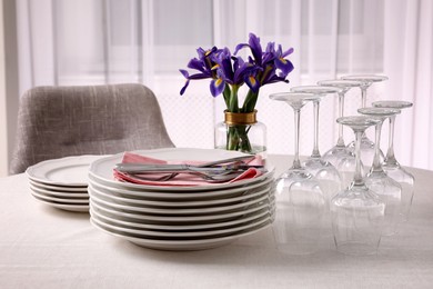 Photo of Set of clean dishware, cutlery and wine glasses on table indoors