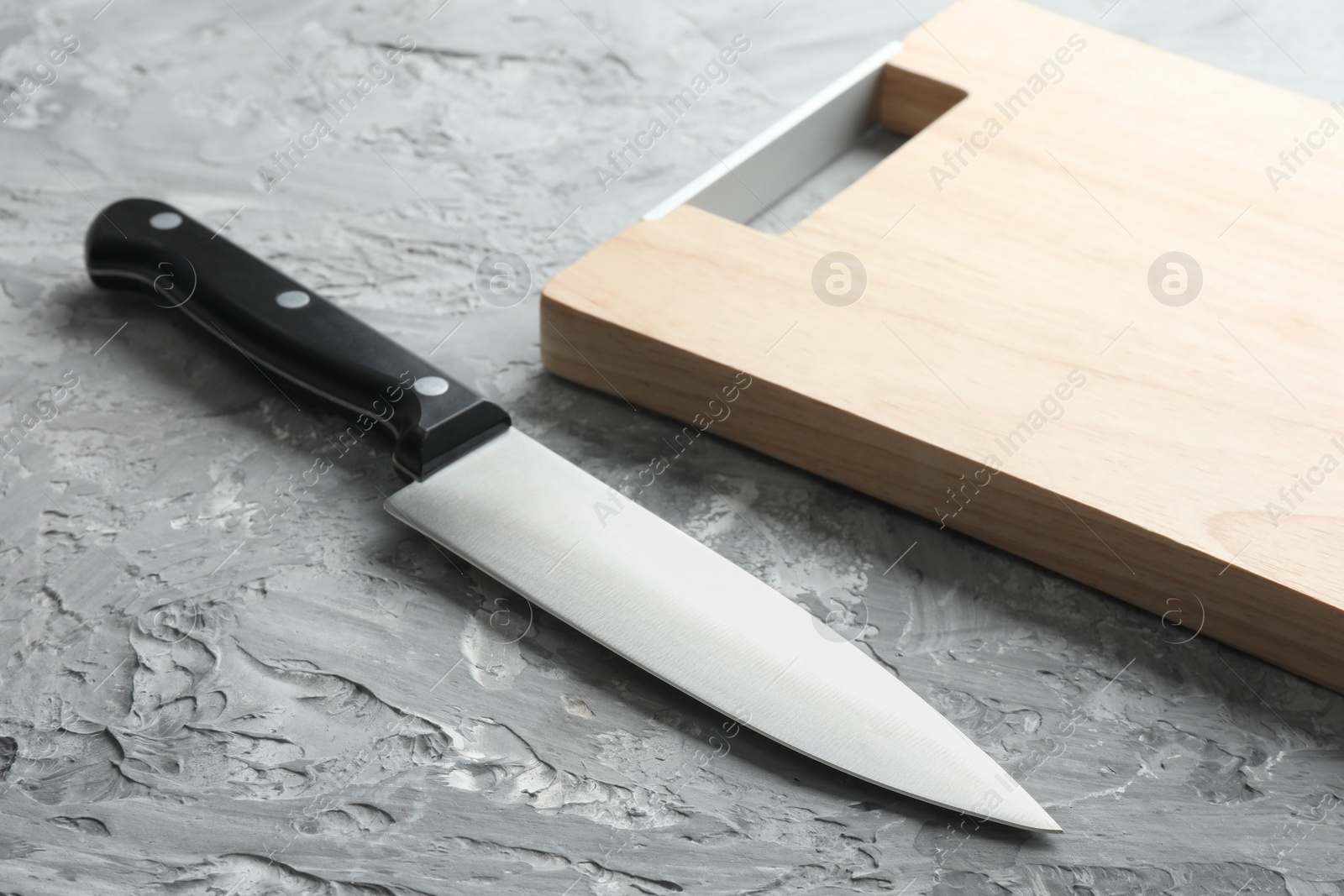 Photo of Knife and wooden board on grey textured table