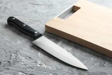 Knife and wooden board on grey textured table