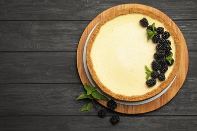 Photo of Delicious cheesecake decorated with blackberries on wooden table, flat lay. Space for text