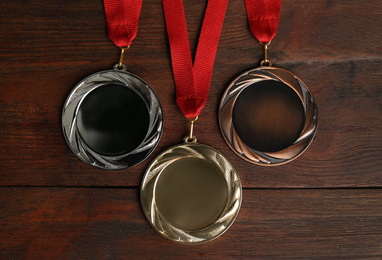 Gold, silver and bronze medals on wooden background, flat lay. Space for design