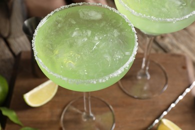 Delicious Margarita cocktail with ice cubes in glasses on table, closeup