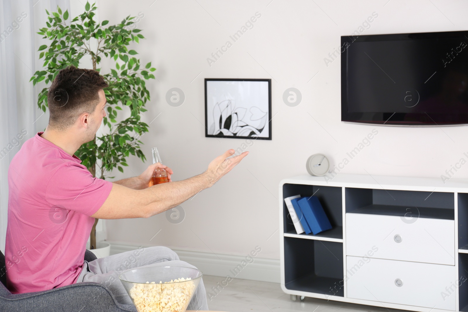 Photo of Handsome young man watching TV in armchair at home