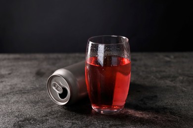 Energy drink in glass and aluminium can on grey table