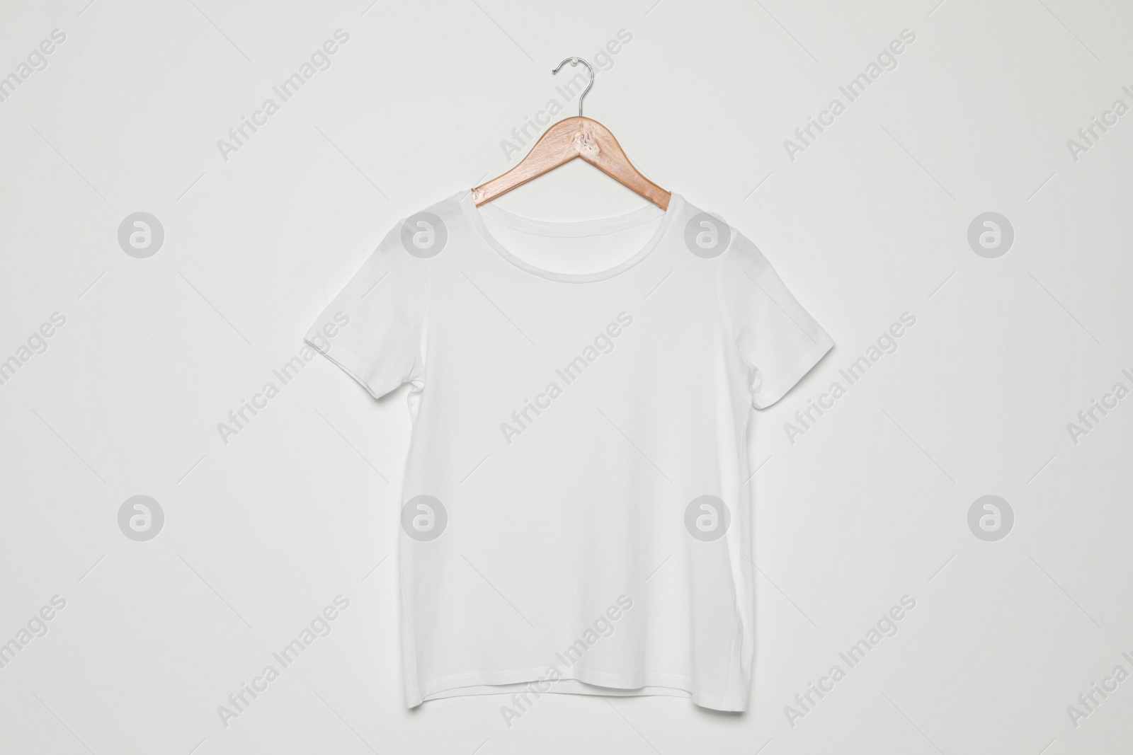 Photo of Hanger with blank t-shirt on white background. Mock up for design