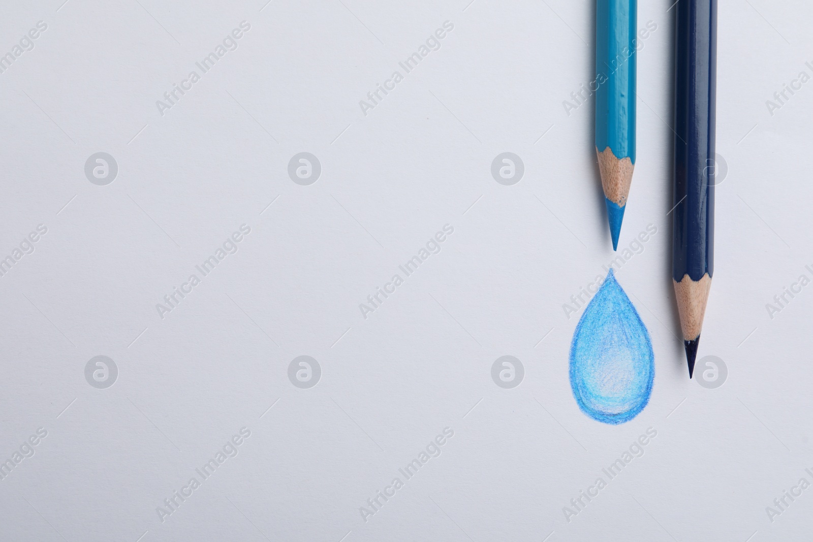 Photo of Drawing of water drop and colorful pencils on white background, top view
