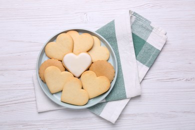 Photo of Heart shaped cookies and napkin on white wooden table, flat lay