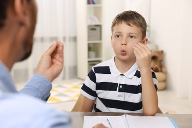Dyslexia treatment. Speech therapist working with boy at table in room
