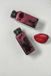 Photo of Bottles of tasty beet smoothies on light background, top view