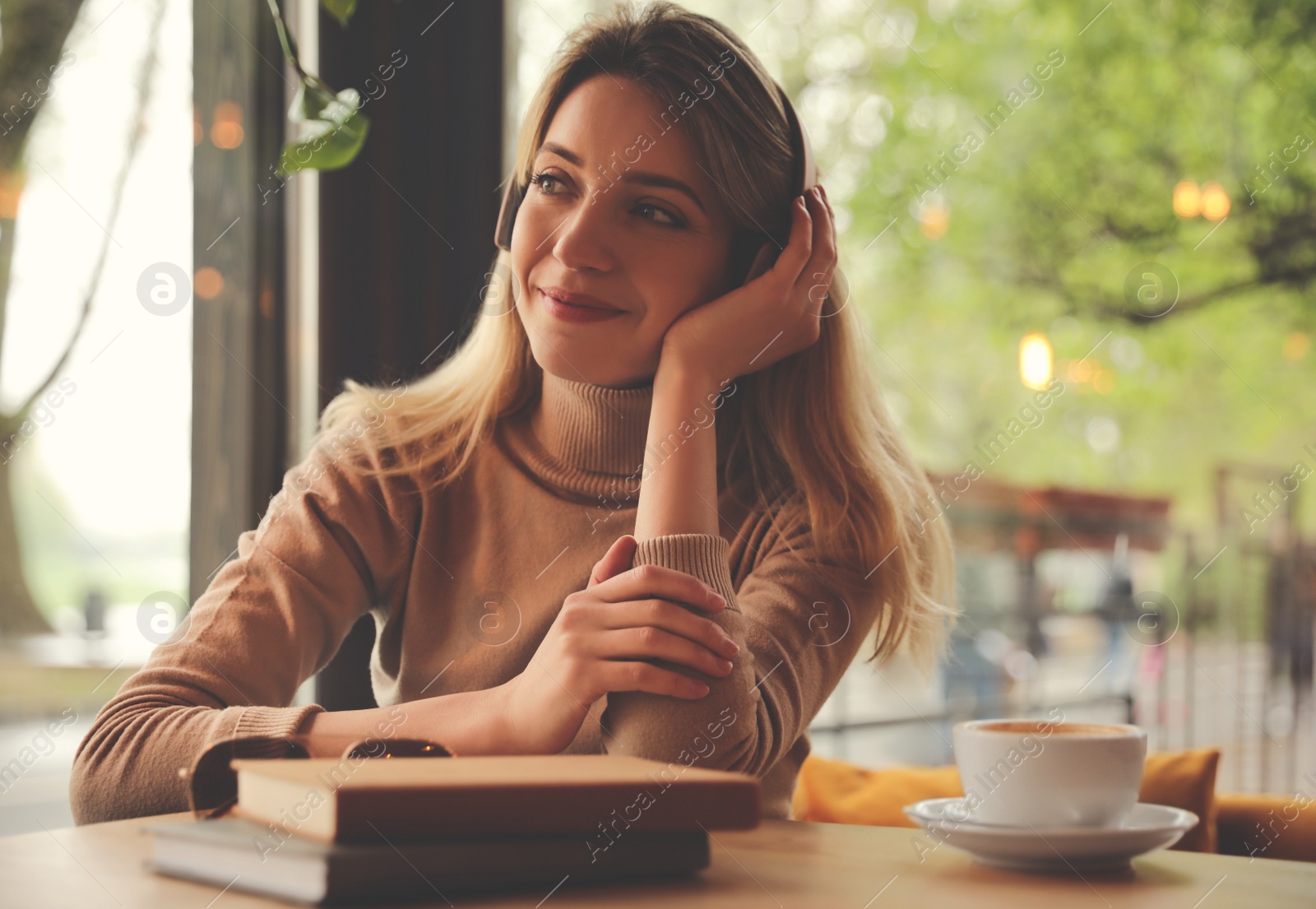 Photo of Woman listening to audiobook at table in cafe