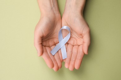 International Psoriasis Day. Woman with light blue ribbon as symbol of support on green background, top view