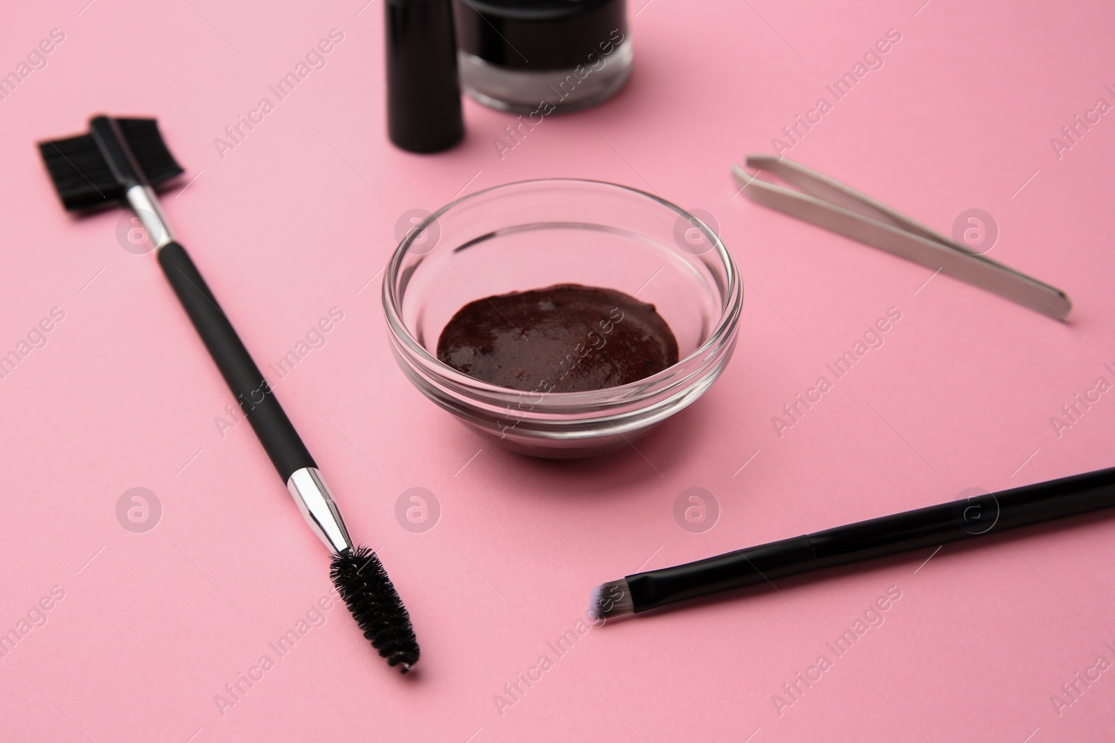 Photo of Eyebrow henna and professional tools on pink background, closeup