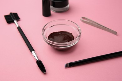Photo of Eyebrow henna and professional tools on pink background, closeup