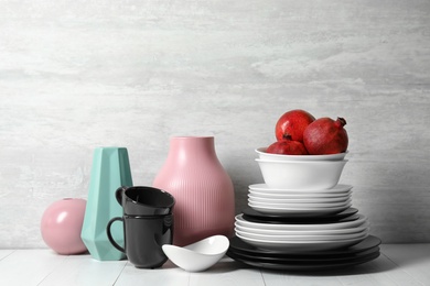Photo of Composition with dinnerware and vases on table against light background. Interior element