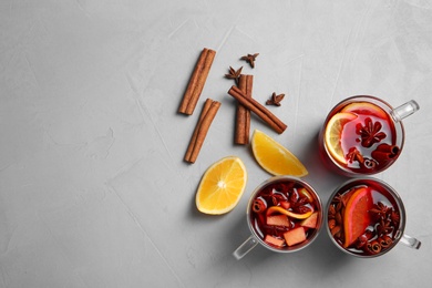 Photo of Flat lay composition with cups of hot mulled wine and space for text on gray background