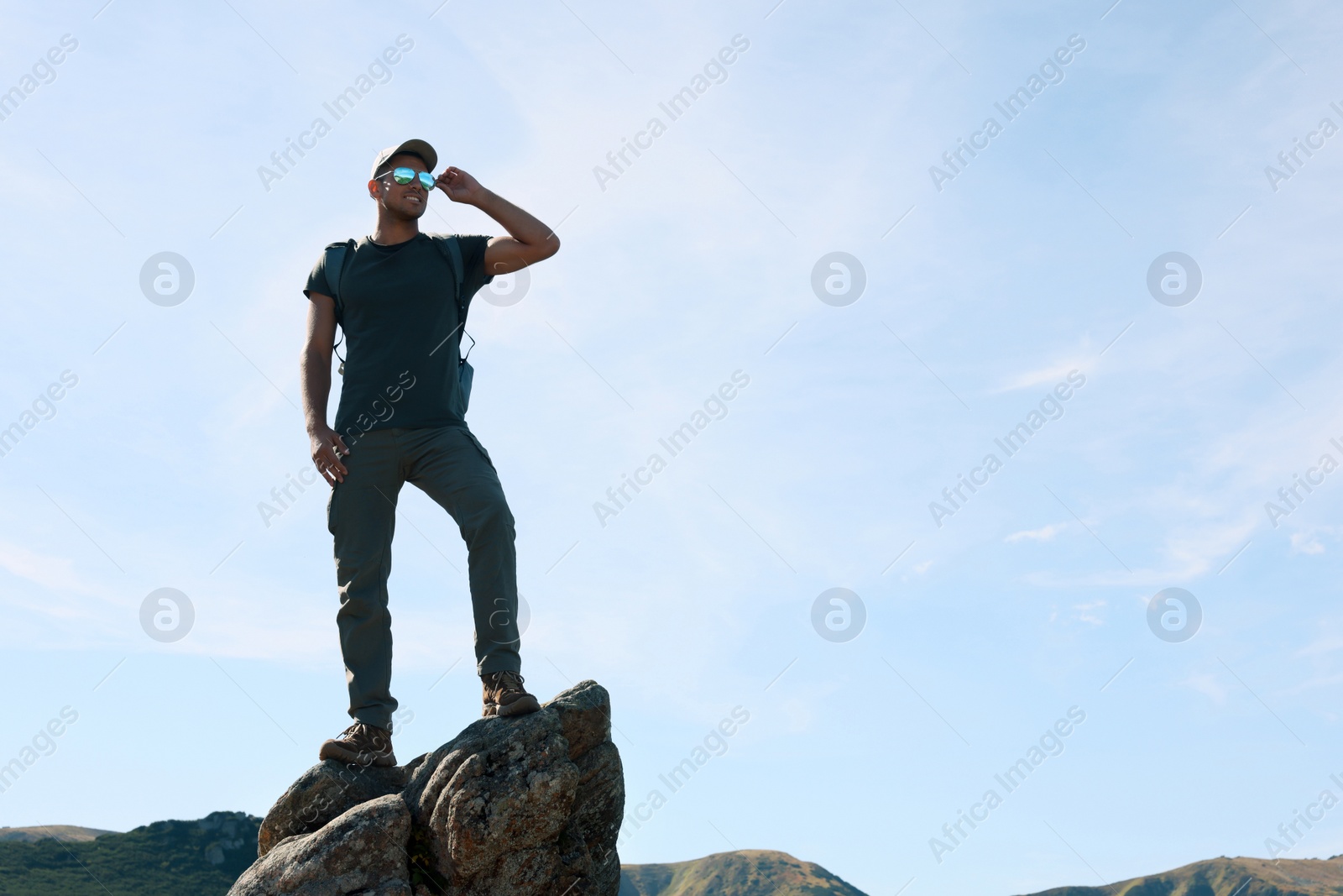 Photo of Man enjoying picturesque view on cliff in mountains. Space for text