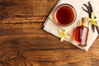 Homemade vanilla extract on wooden table, flat lay. Space for text