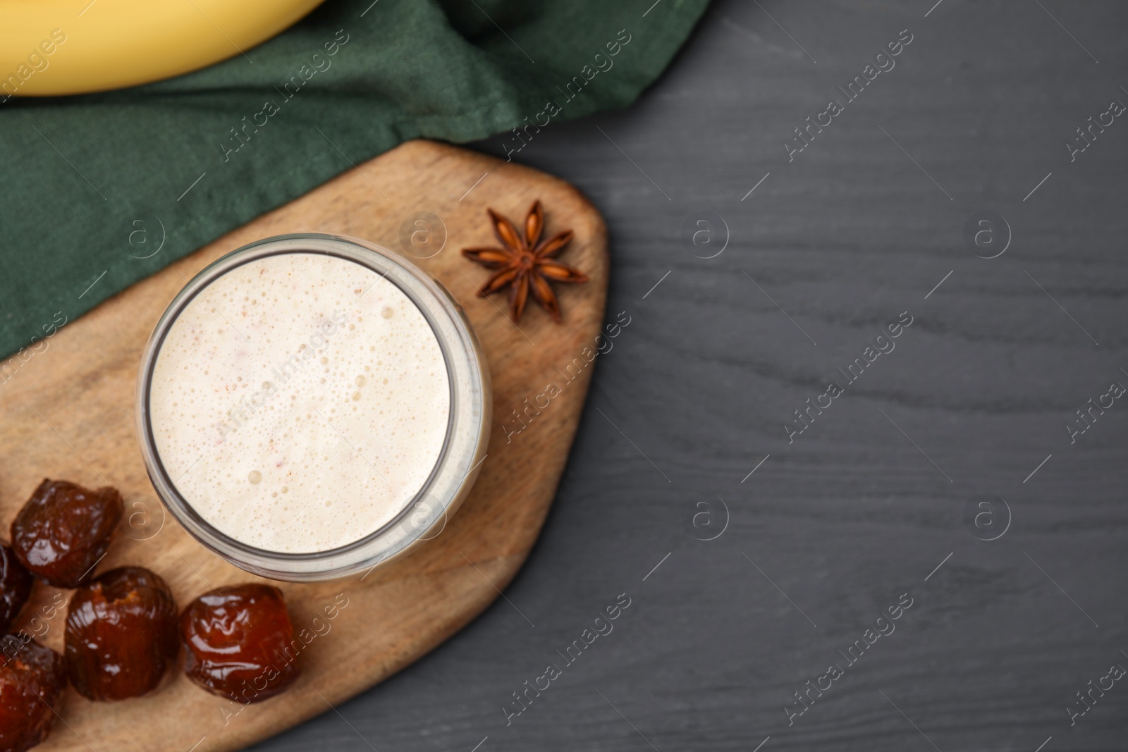 Photo of Glass of delicious date smoothie, dried fruits and anise on grey wooden table, flat lay. Space for text