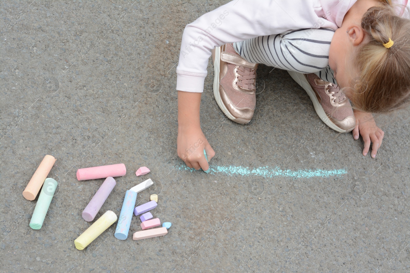 Photo of Little child drawing happy family with chalk on asphalt, above view