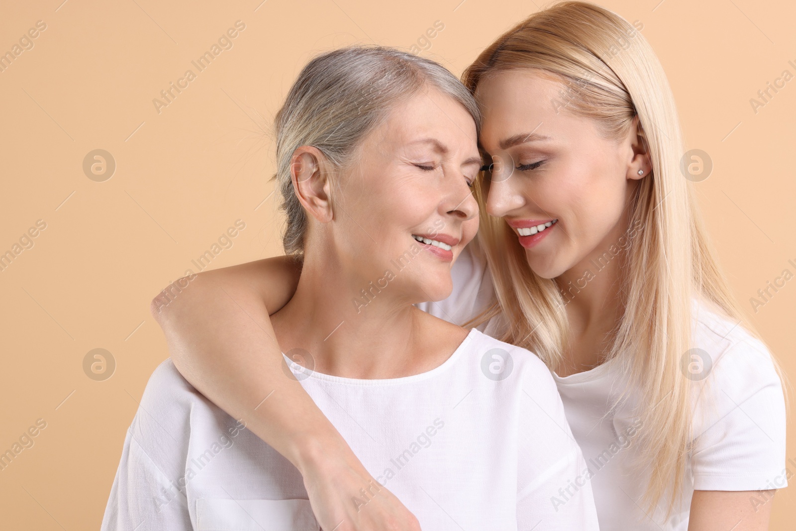 Photo of Family portrait of young woman and her mother on beige background