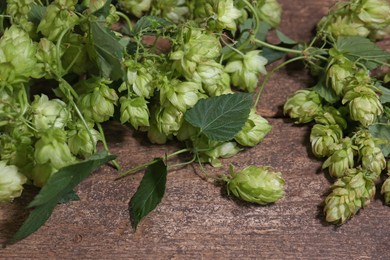 Photo of Fresh green hops with leaves on wooden table, closeup