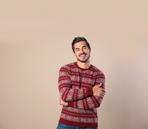 Portrait of happy man in Christmas sweater on beige background