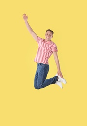 Photo of Happy teenage boy jumping on yellow background