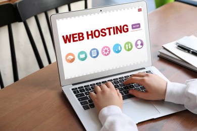 Image of Web hosting service. Woman using laptop at wooden table indoors, closeup