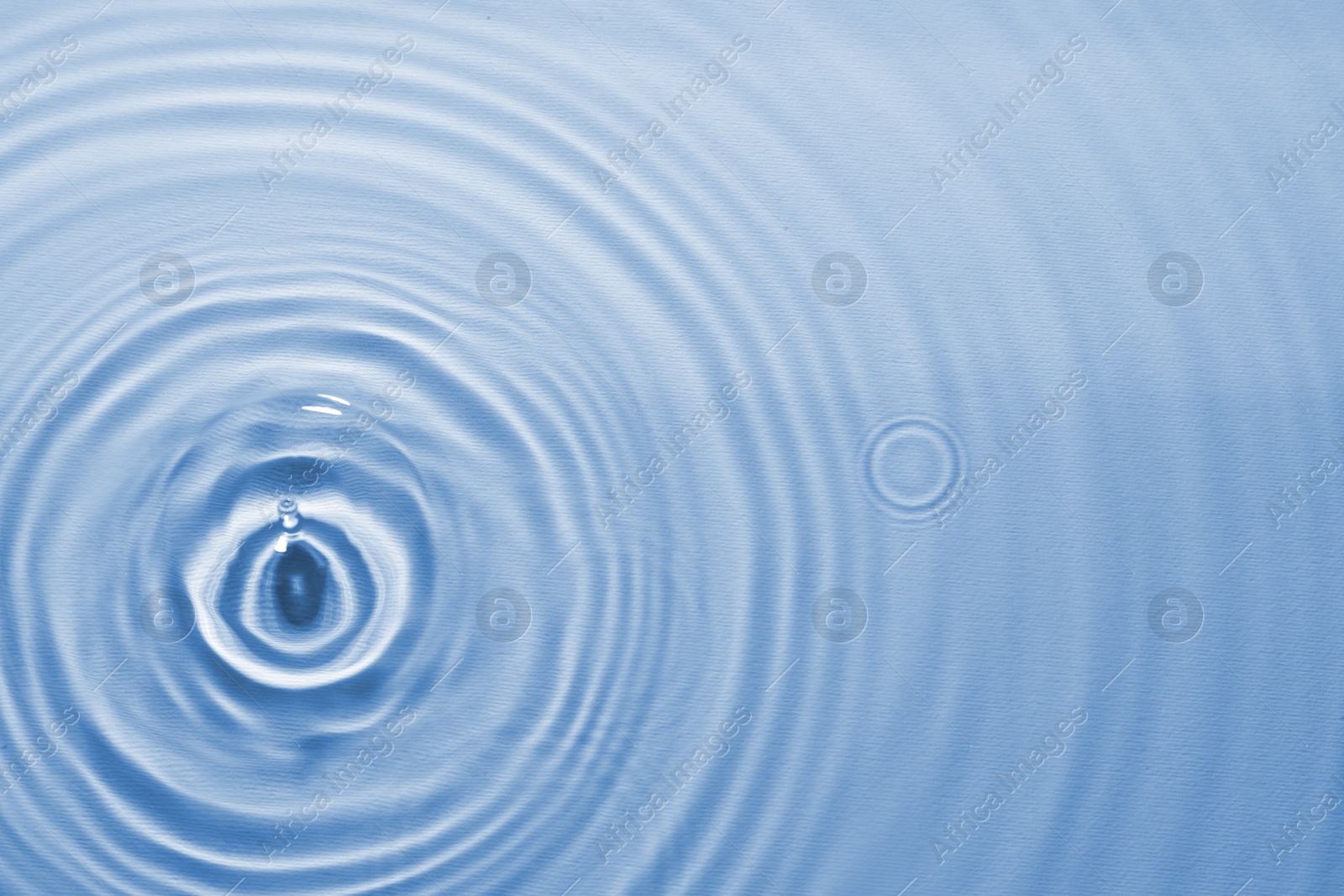 Image of Rippled surface of clear water on light blue background, top view