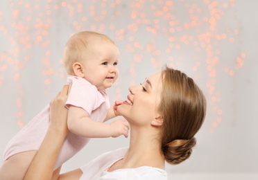 Photo of Portrait of happy mother with her baby against blurred lights