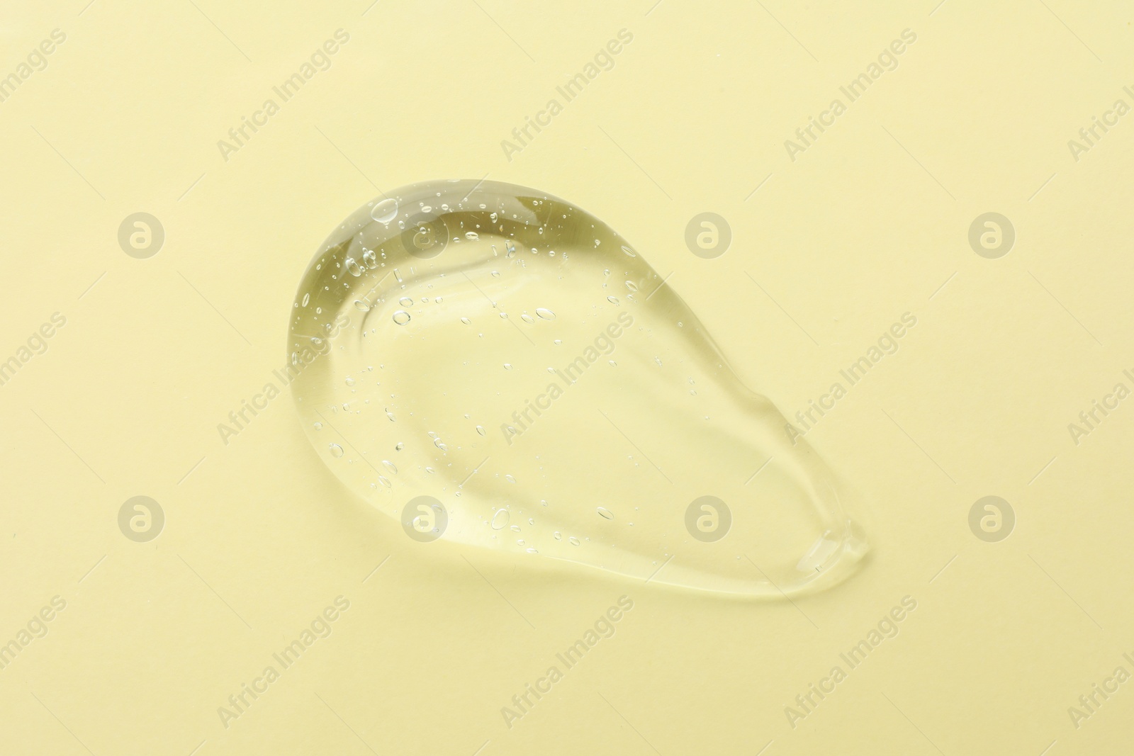 Photo of Clear cosmetic gel on yellow background, top view